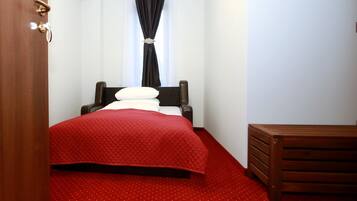Una habitación de hotel con una cama, un banco de madera y una alfombra roja.
