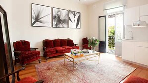 A living room with a red sofa, a coffee table, and a rug. There are three framed pictures on the wall.