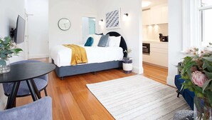 A modern bedroom with a bed, bedside table, and a small round table with chairs. - Beautiful Studio in Heritage Building with Balcony (Lewsiham)
