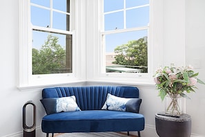Relax in this cozy corner room with a sofa, potted plant, and a view of the surrounding greenery.