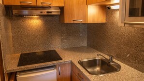 Une cuisine dotée de plans de travail en granit, d’un évier en acier inoxydable, de meubles en bois et d’une cuisinière encastrée.