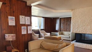 Un salon chaleureux avec un mur en bois, un canapé beige, une petite table et une cheminée.