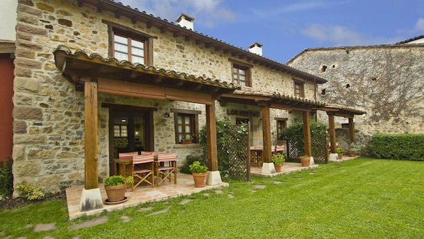 Un edificio in pietra con un patio, area relax con sedute all'aperto e vasi di piante.