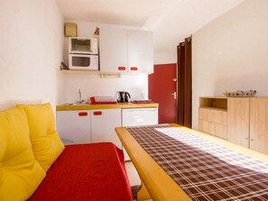 Cozy retreat with a kitchenette, microwave, and small oven, featuring a comfortable bed and a wooden table.