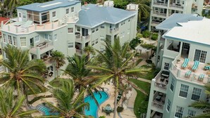 Um hotel de vários andares com piscina, rodeado por palmeiras.