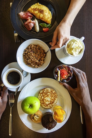 A breakfast table with various dishes including pancakes, a fruit bowl, and a coffee cup.