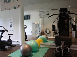 A gym with exercise equipment, including stationary bikes and a weight machine, and exercise balls on mats. - ibis Styles Arlon Porte du Luxembourg (Arlon)