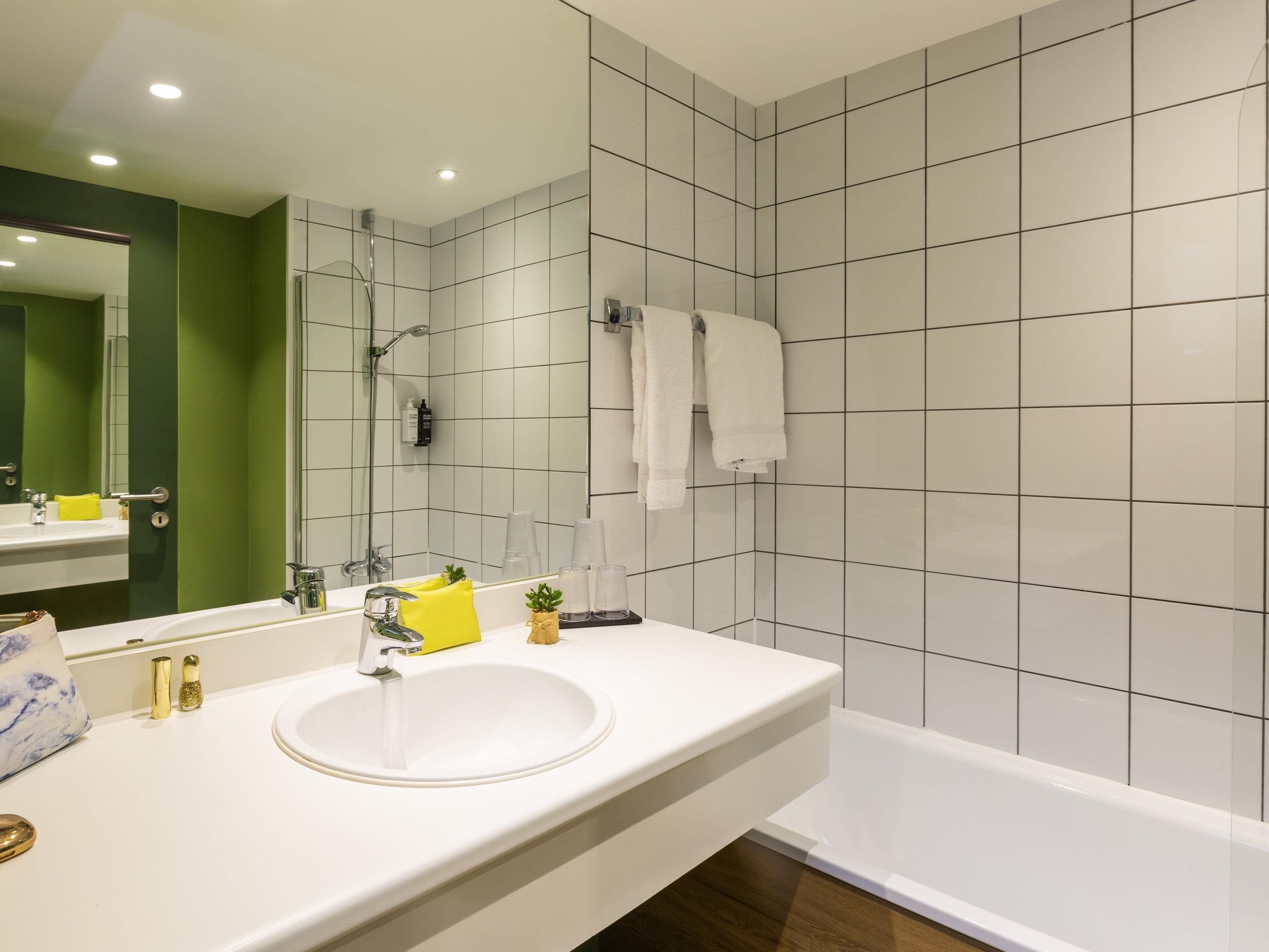 A modern bathroom with a white sink, a mirror, and a bathtub.
