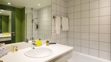 A modern bathroom with a white sink, a mirror, and a bathtub.