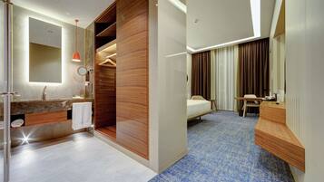 Une chambre d’hôtel moderne équipée d’une salle de bain, d’un lit, d’un bureau et d’un miroir.