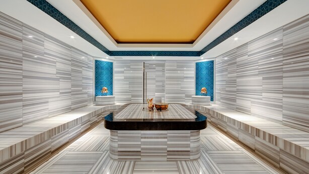 A modern bathroom with a central marble sink, tiled walls, and a yellow ceiling. - DoubleTree by Hilton Adana (Adana)