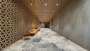 A hallway with patterned walls, a carpeted floor, and seating areas with cushions. - DoubleTree by Hilton Adana (Adana)