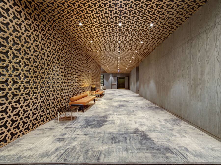 Un couloir aux murs ornés de motifs, doté d’un sol recouvert de moquette et aménagé avec des coins salon équipés de coussins.