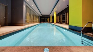 A modern indoor swimming pool with clear blue water, surrounded by glass walls and a tiled floor. - DoubleTree by Hilton Adana (Adana)