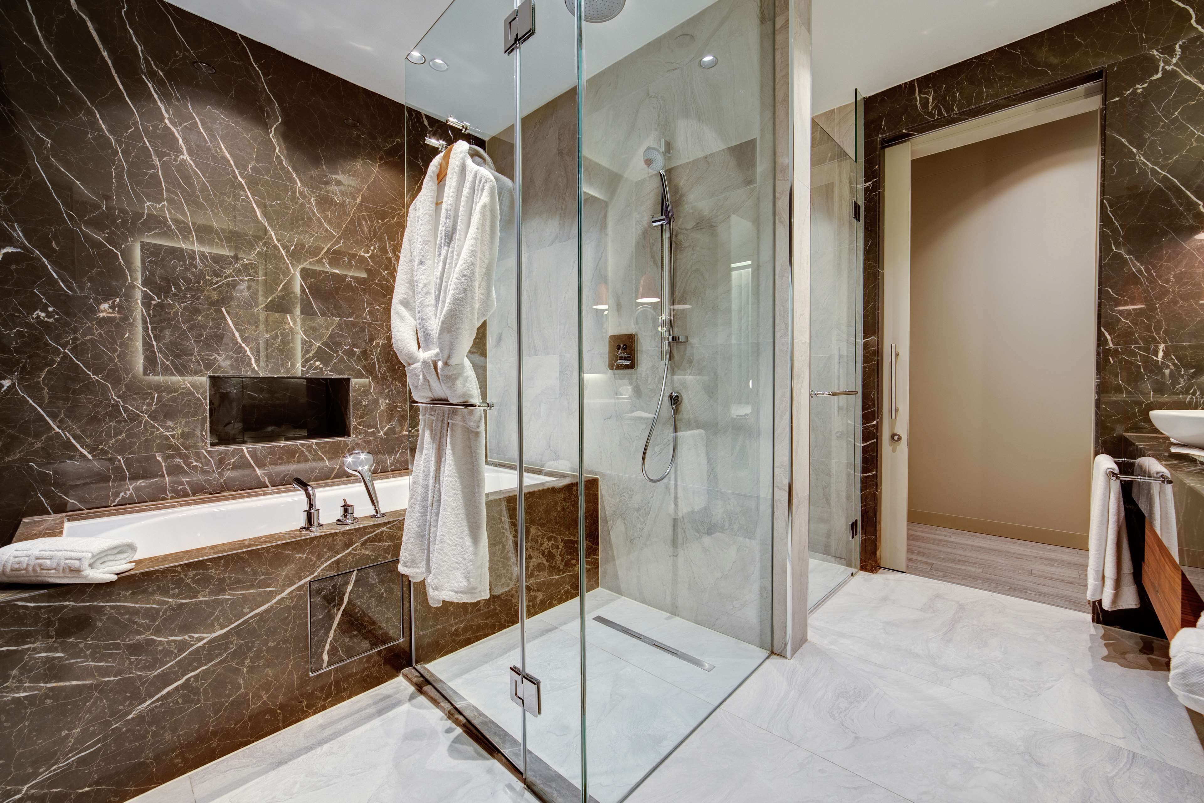 Un baño moderno con ducha envuelta en vidrio, una bañera y un tocador con espejo.