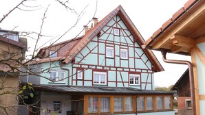 A traditional half-timbered house with a sloped roof, a wooden front porch, and a brick chimney. - D´r Rechenmacher Pension und Landgasthof (Michelfeld)