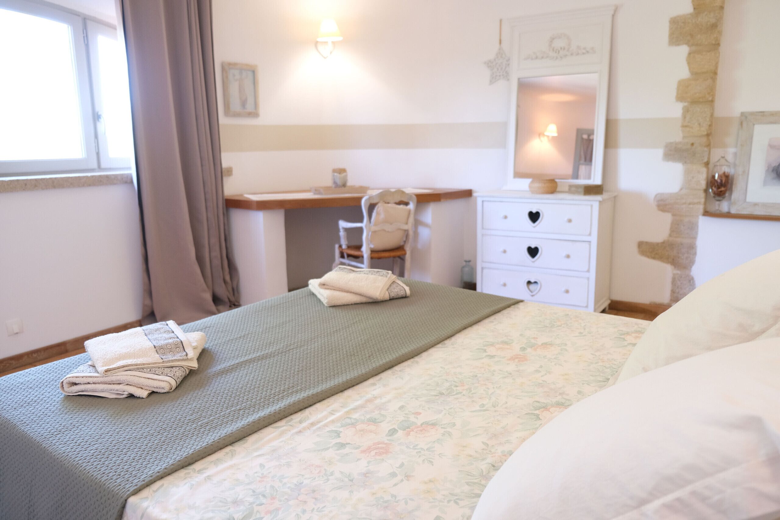 A bedroom with a bed, a desk, a chair, and a dresser.