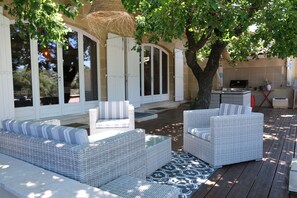 An outdoor seating area with wicker furniture and a large tree providing shade. - Vacation rental house with pool TAILLADES LS2-352 (Taillades)