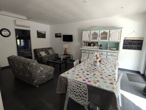 A compact living space with a dining area, a sofa, a TV, and a kitchenette.