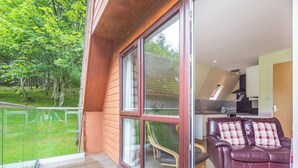 A modern living room with a glass sliding door leading to a balcony. - Gorse Lodge - UK7050 (Rosemarkie, near Fortrose)