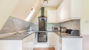 A modern kitchen with white cabinets, a built-in oven, a microwave, and a toaster. - Gorse Lodge - UK7050 (Rosemarkie, near Fortrose)