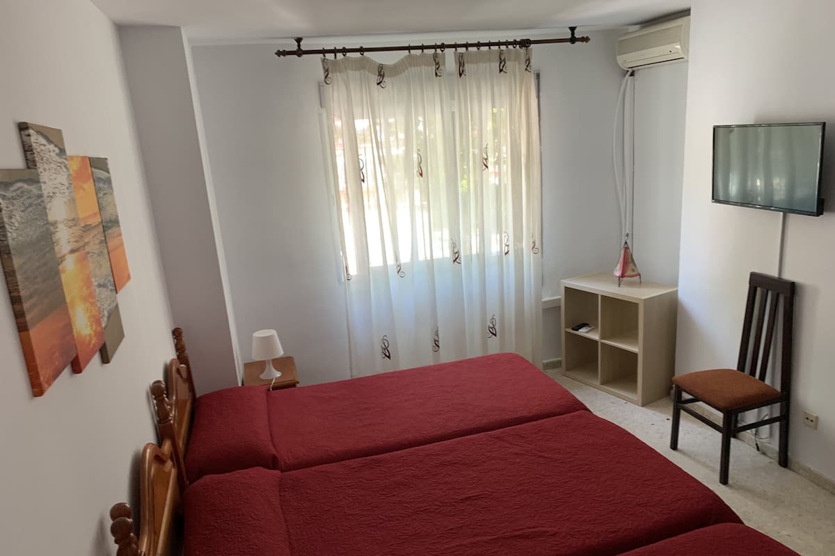 Une chambre avec un grand lit, un téléviseur fixé au mur, une chaise et une étagère.