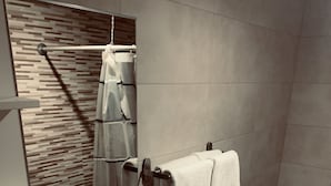Ein modernes Badezimmer mit einem weißen Waschbecken, einem Spiegel, einem Handtuchhalter mit zwei Handtüchern, einer Toilette und einer Duschvorhang.
