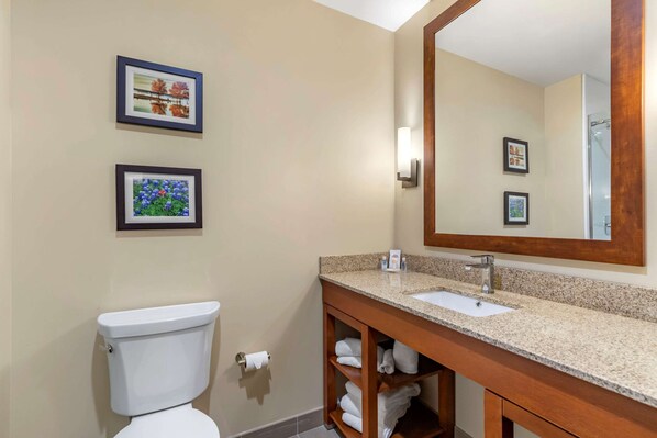A bathroom with a toilet, sink, and mirror. There are two framed pictures on the wall.