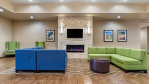 A modern lobby with a stone fireplace, green sofas, and a flat-screen TV. - Comfort Suites San Antonio Ft. Sam Houston/SAMMC Area (San Antonio)