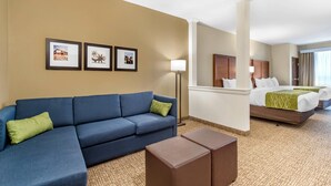 A hotel room with a blue sofa, a bed, a small table, and framed pictures on the wall. - Comfort Suites San Antonio Ft. Sam Houston/SAMMC Area (San Antonio)