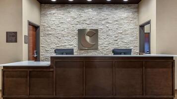 A reception desk with a stone wall backdrop, two computer stations, and a wooden panel design.