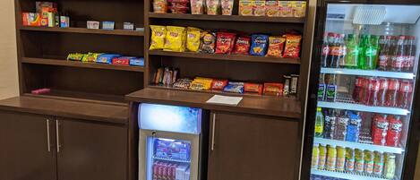 Un espace proposant des distributeurs automatiques de collations et de boissons, avec un assortiment varié de produits.