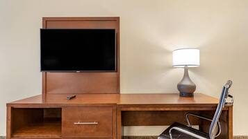 A wooden desk with a flat-screen TV, a lamp, and a chair.