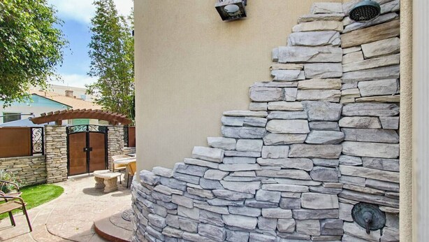 A stone wall with a curved design, a gated entrance, and outdoor seating. - New Photos! Luxury Steps to Beach w/hot tub garage (San Diego)
