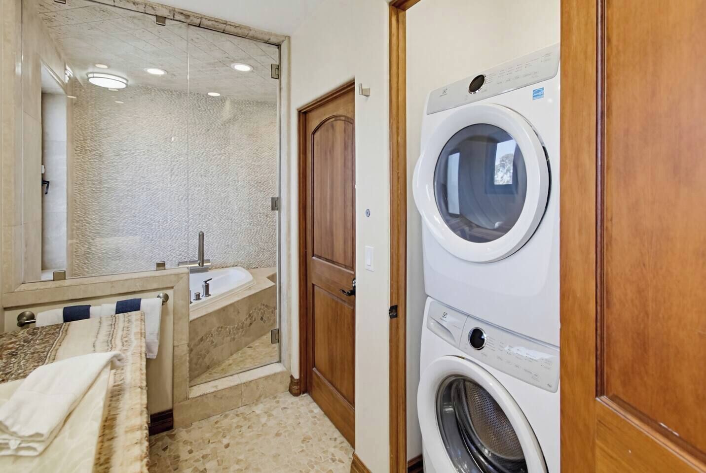 Ein kleines Badezimmer mit Spiegel, Waschbecken und übereinandergestellter Waschmaschine.