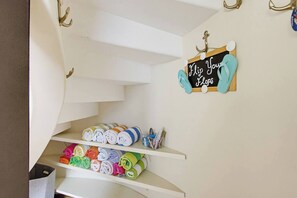 A staircase with multiple levels, each with shelves holding folded towels in various colors. A sign on the wall reads 'Flip Your Flops.'