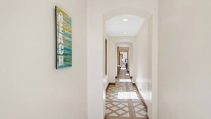 A hallway with a geometric patterned floor, a painting on the wall, and an arched ceiling. - New Photos! Luxury Steps to Beach w/hot tub garage (San Diego)