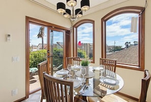 A dining area with a round glass table, wooden chairs, and a ceiling light fixture.