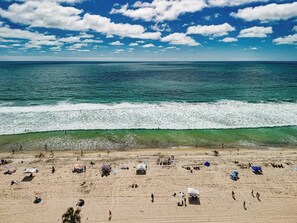 A beach with people, umbrellas, and a clear sky.