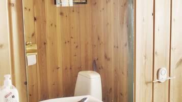 Un baño con paneles de madera, un lavamanos blanco con grifo cromado, un espejo y un inodoro.