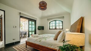Ein Schlafzimmer mit Bett, Nachttischlampe, Fernseher und Blick ins Freie.