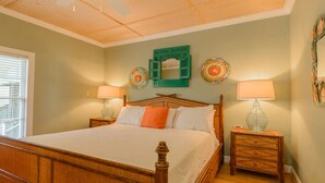 Une chambre à coucher avec un lit en bois, deux tables de chevet avec des lampes, un ventilateur de plafond et des assiettes décoratives accrochées au mur.