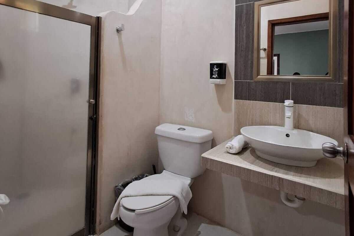 A compact bathroom with a toilet, sink, and shower.