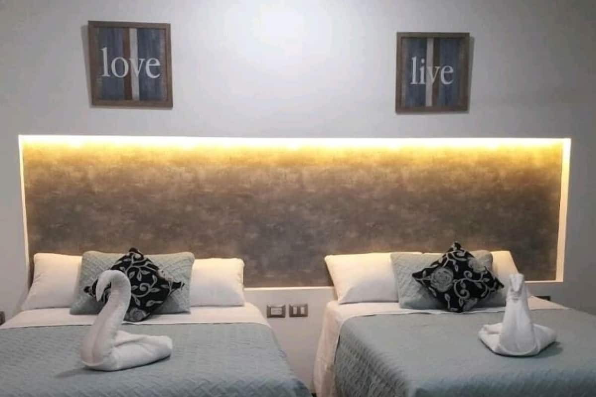 Two twin beds with matching headboards, each adorned with a swan decoration and a pillow. The room features a textured wall with 'love' and 'live' framed on the upper part.