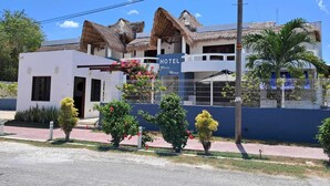 A hotel with a white exterior, a blue sign, and a thatched roof. - Maria-Maria Hotel (Bacalar)