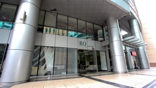 Un bâtiment moderne doté d’une façade en verre et d’un grand panneau affichant les lettres « RQ ».