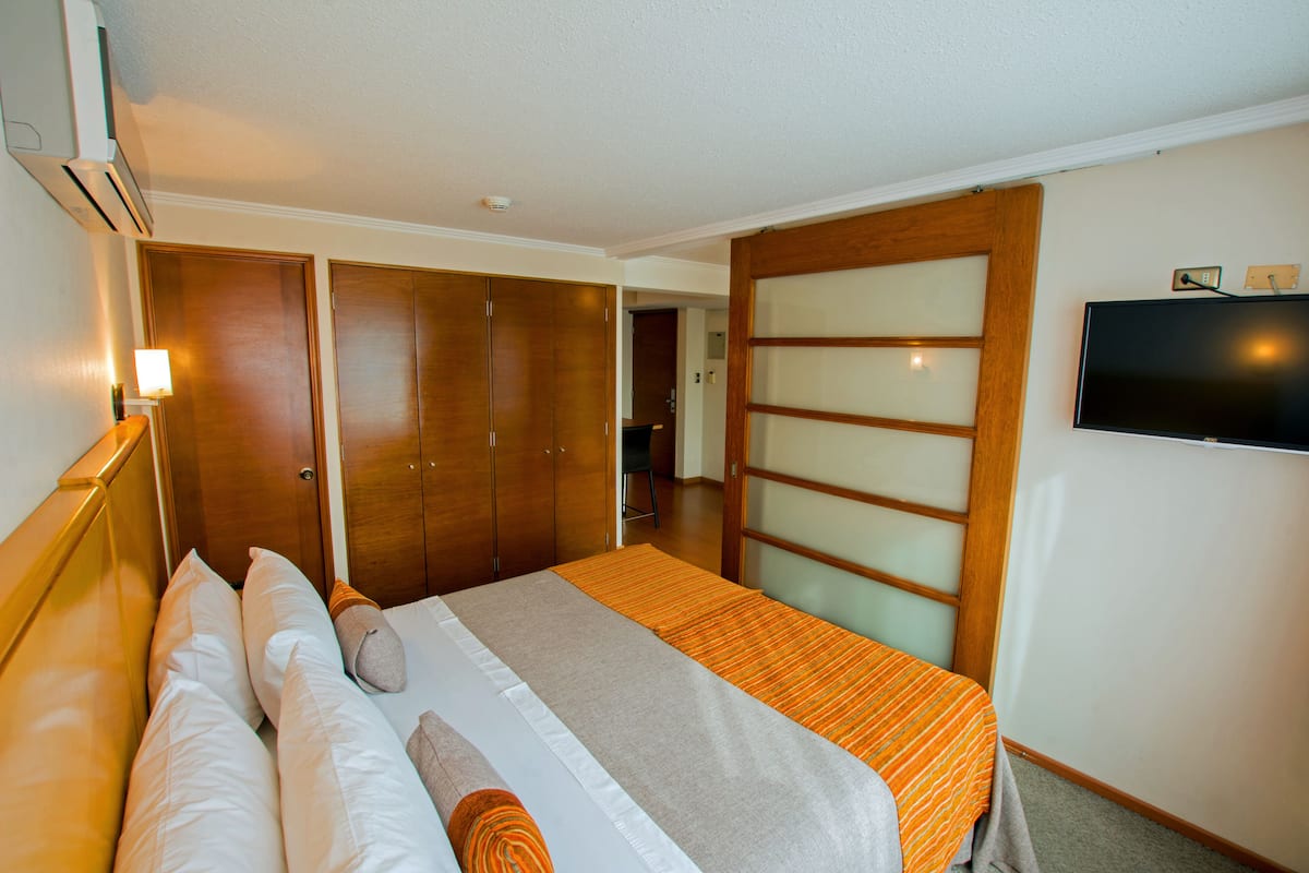 Ein Hotelzimmer mit Bett, Fernseher und Kleiderschrank.