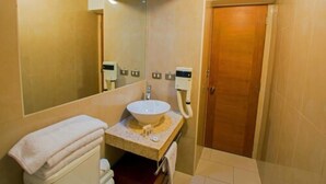 Une salle de bain avec un grand miroir, un lavabo, des toilettes et un espace douche.