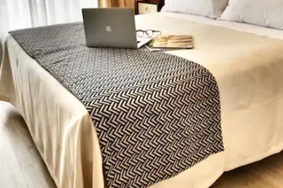 Une chambre d’hôtel avec un lit, un ordinateur portable et une table de chevet avec une lampe.