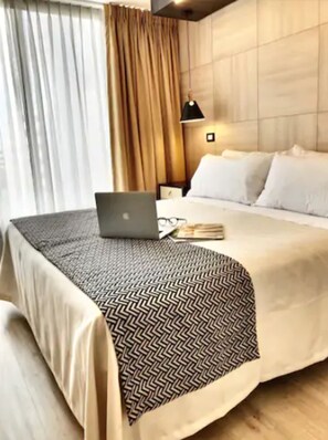 A hotel room with a bed, a laptop, and a bedside table with a lamp. - RQ Express Costanera (Santiago)